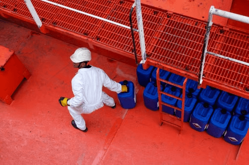 Operator handling chemical containers on a plant deck